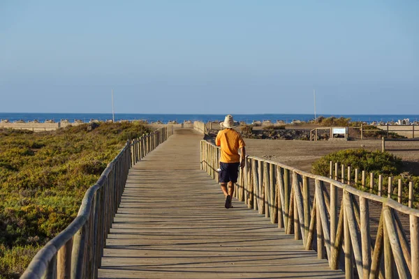 Personas corriendo en una pasarela de dunas cerca del mar al atardecer —  Fotos de Stock