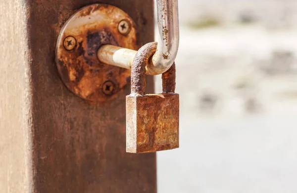 Imagem do cadeado mostrando um velho cadeado enferrujado montado em uma cerca pela costa — Fotografia de Stock