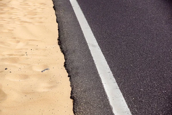 Asphaltweg mit weißer Fahrbahnmarkierung im Wüstensand — Stockfoto