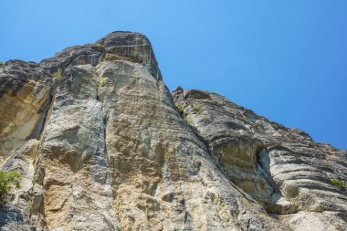 mavi gökyüzüne kadar uzanan bir dağın kayalık duvar .