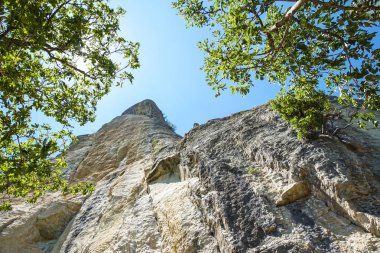 mavi gökyüzüne kadar uzanan bir dağın kayalık duvar .