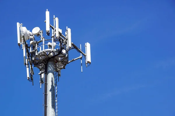 Partie supérieure de la tour de communication de téléphone portable avec plusieurs antennes contre un ciel bleu — Photo