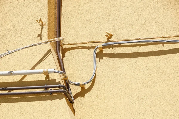 Cavi elettrici, cavi telefonici e tubi metallici per l'acqua di fronte a una vecchia facciata dell'edificio — Foto Stock