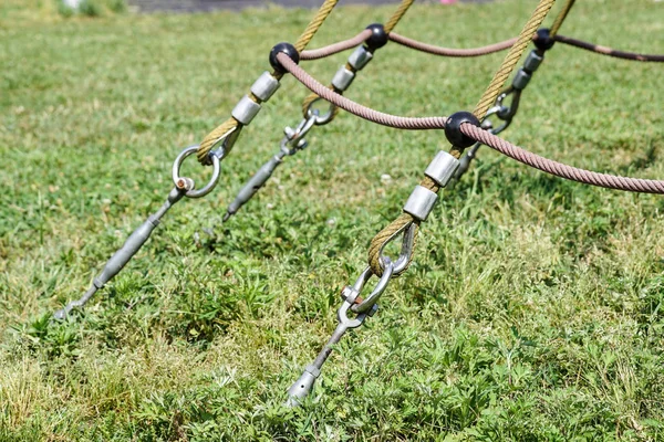 Slutet av swinging repet hänga på metall konstruktion i en park. Grova rep slutet i metall cirklar och säkerhet snapin krok — Stockfoto