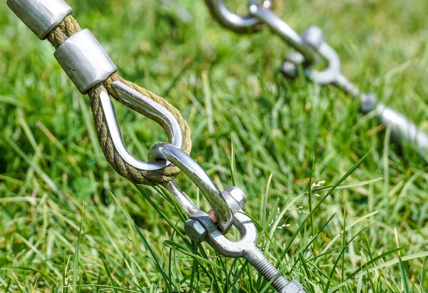 Slutet av swinging repet hänga på metall konstruktion i en park. Grova rep slutet i metall cirklar och säkerhet snapin krok — Stockfoto