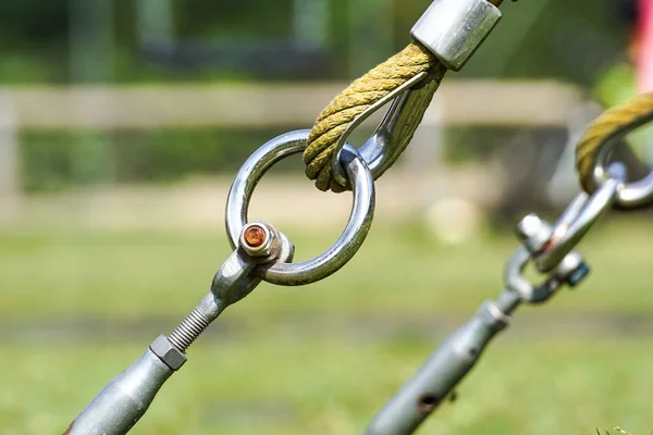 Slutet av swinging repet hänga på metall konstruktion i en park. Grova rep slutet i metall cirklar och säkerhet snapin krok — Stockfoto