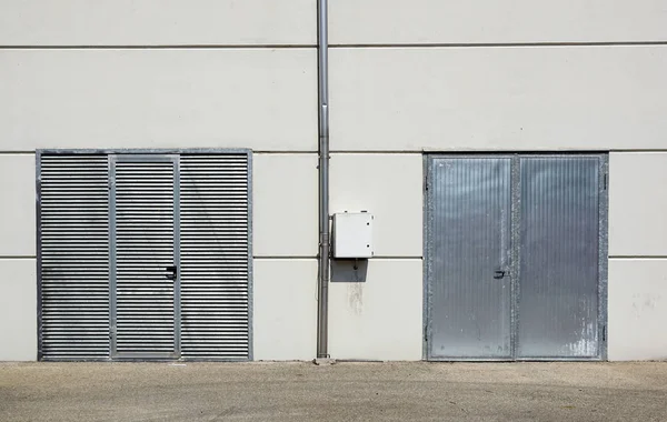 White Overhead Steel Garage Door On Exterior of Beige Metal Building with Red Bumper posts — стоковое фото