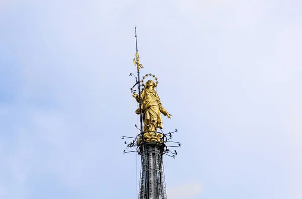 A Madonnina no topo da Catedral de Milão, no auge de 108,5 m em Milão, itália. Milão Duomo é a maior igreja da Itália. Arquitetura histórica de Milão. Madonna dourada no fundo do céu azul . — Fotografia de Stock