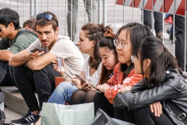 Milan, İtalya, 04 Mart 2018: Kent Meydanı'nda oturan genç insanlar iletişim kurmak onların smartphone kullanarak.