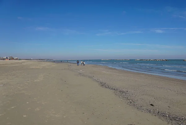 Vierköpfige Familie hält sich an den Händen und geht am Strand spazieren — Stockfoto