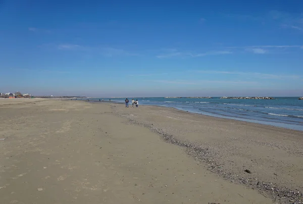 Family of four holding hands and walking on beach — Stock Photo, Image