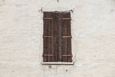 Terk edilmiş, harap olmuş eski ahşap pencereler ve yıpranmış eski çatısı ve yıpranmış boyası olan bir duvar. Yakın plan..