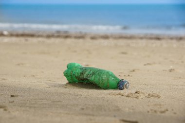 Plastik şişeyi kuma boşalt. Kumsalda çöp.