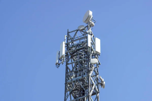 Закрыть белый цвет антенны ретранслятора башня на голубом небе — стоковое фото