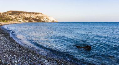 Batan güneşin son ışınları Aphrodite Bay Kıbrıs sahil çevresinde kırmızı dağlar boyalı.