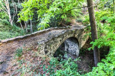 Batan güneşin son ışınları antik taş kemer Troodos dağ orta kısmında Venedik köprü aydınlatılmış.
