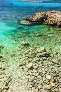 Akdeniz'in berrak suları Kıbrıs adasında kayalık sahil üzerinde yıkama.