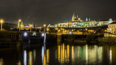 Gece ışıkları eski Prag Vltava Nehri sessiz, karanlık sularda yansıtılır.
