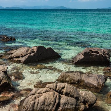 Andaman denizinin dalgaları küçük bir tropikal adada kıyı kayaları arasında tur atıyor..