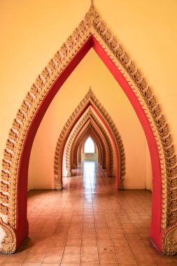 Kaplanın Tayland tapınağındaki karmaşık şekilli kemerler sonsuzluğa uzanan bir galeri yaratıyor.