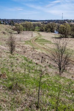 Çamurlu, dolambaçlı bir köy yolu nehir kıyısından geçer ve tepeden çıkıp küçük bir eve gider..