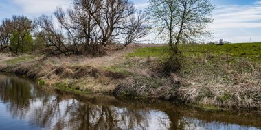 Baharın başlarında, mavi gökyüzü ve çıplak ağaçlar Orta Rusya 'daki Lopasnya nehrinin sularına yansıyor..