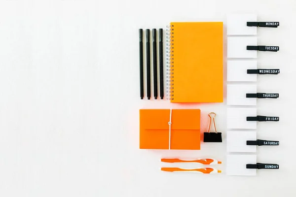 Orange colored office stationery with simple weekday organizer on white background