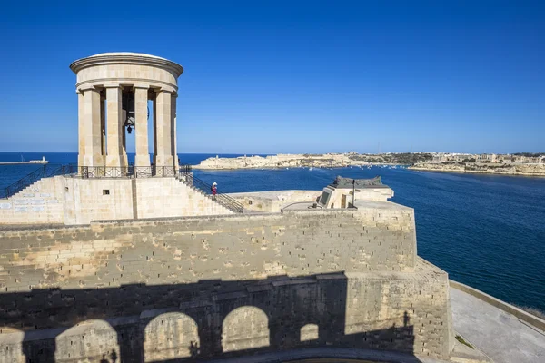 Valletta, Malta - Siege Bell válečný památník v Grand Harbor Valletta s turisty a jasně modré obloze — Stock fotografie