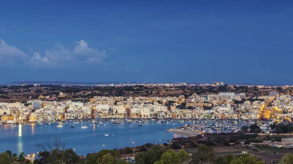 Marsaxlokk, Malta - Vista panorâmica do horizonte de Marsaxlokk, a tradicional aldeia de pescadores de Malta ao nascer do sol com céu azul e belas nuvens — Fotografia de Stock