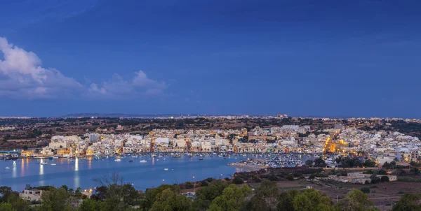 Marsaxlokk, Malta - Vista panorámica del horizonte de Marsaxlokk, el tradicional pueblo de pescadores de Malta al amanecer con cielo azul y hermosas nubes — Foto de Stock