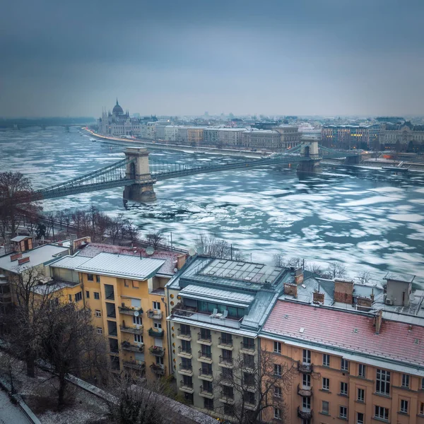 Будапешт, Венгрия - потрясающий вид на Цепной мост на ледяной реке Дунай с Парламентом и Базиликой на фоне зимнего утра — стоковое фото