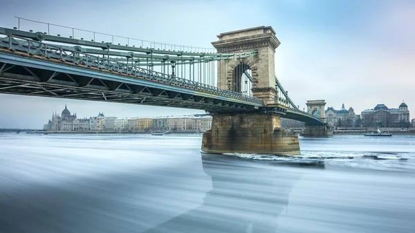 Будапешт, Венгрия - знаменитый Цепной мост на ледяной реке Дунай холодным зимним утром на фоне венгерского парламента — стоковое фото