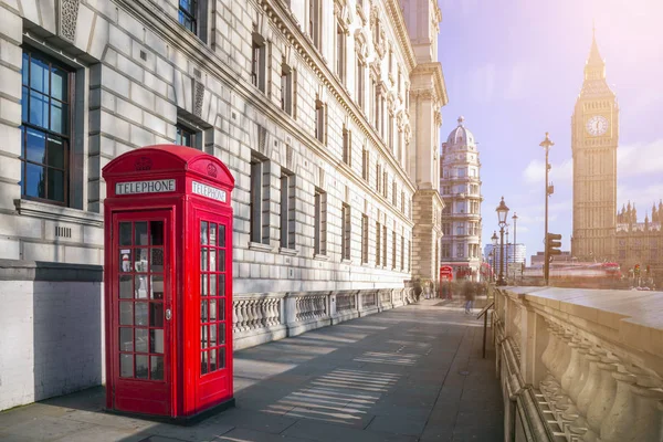 London, Anglia - hagyományos piros brit telefonfülke, Big Ben és emeletes busz a háttérben egy napsütéses délutánon, a blue sky és clouds — Stock Fotó
