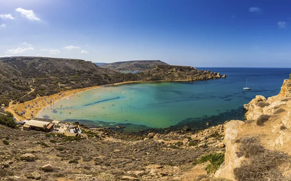 Ghajn Tuffieha, Malta - Hermoso día de verano en la playa de arena Ghajn Tuffieha con velero, cielo azul y agua de mar verde cristalina — Foto de Stock