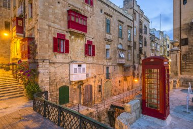 Valletta, Malta - kırmızı vintage İngiliz telefon kulübesi ve yaya köprüsü ve eski şehir Valletta sabahın erken saatlerinde geleneksel kırmızı balkon