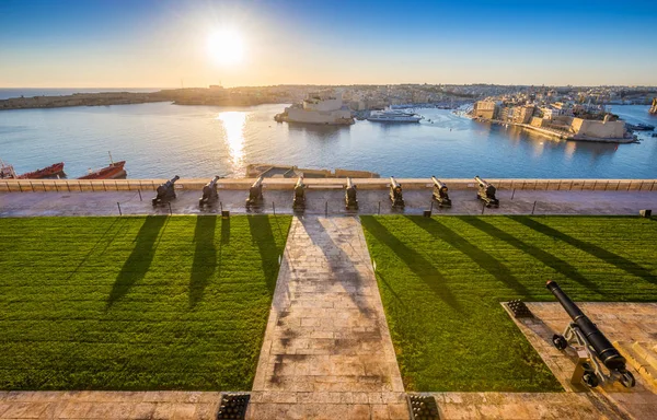 Valletta, Malta - Beautiful sunrise at the famous saluting battery of Valletta with Grand Harbor and Senglea and Brigu at background. Blue sky and sunlight. — Stock Photo, Image