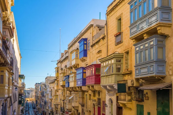 Valletta, Malta - typiska smal gata med färgglada traditionella fönster och balkonger och klarblå himmel på en sommardag — Stockfoto