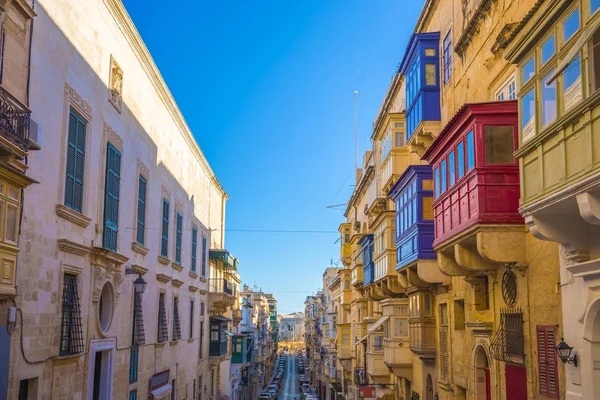 Valletta, Malta - typowy wąskiej uliczce z kolorowe tradycyjne okna i balkony i błękitne niebo w letni dzień — Zdjęcie stockowe