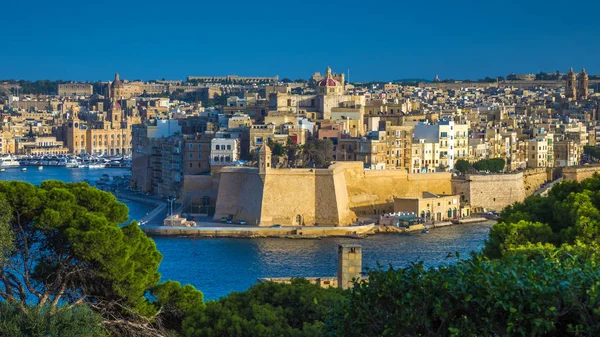 Valletta, Malta - A vista de Valletta com árvores, Ilha de Senglea, Jardins Gardjola com torre de vigia, o Grande Porto com barcos e navios e céu azul claro — Fotografia de Stock