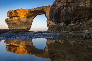 Gozo, Malta - güzel Azure pencere, doğal bir kemer ve ünlü dönüm noktası yansıması ile Gozo Adası üzerinde güneş doğarken. Mart, 2017 9 üzerinde daraltılmışsa