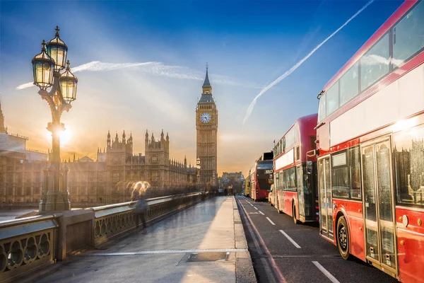 Londres, Inglaterra - O icônico Big Ben e as Casas do Parlamento com poste de lâmpada e famosos ônibus vermelhos de dois andares na ponte Westminster ao pôr-do-sol com céu azul — Fotografia de Stock