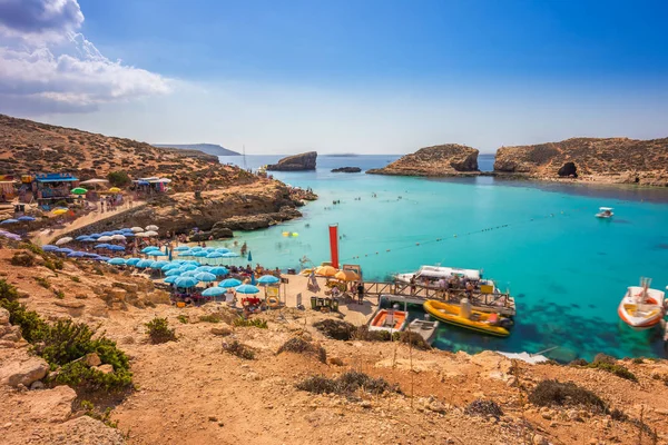 Comino, Malte - Les touristes affluent à Blue Lagoon pour profiter de l'eau turquoise claire par une journée ensoleillée d'été avec un ciel bleu clair et des bateaux sur l'île de Comino, Malte . — Photo