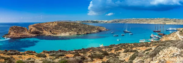 Κομίνο, Μάλτα - θέα πανοραμική στον ορίζοντα της διασημότερης και ομορφότερης Blue Lagoon σχετικά με το νησί Κομίνο με ιστιοφόρα, παραδοσιακές βάρκες Luzzu και τουρίστες απολαμβάνουν την γαλάζια Μεσόγειο θάλασσα νερό και τον ήλιο — Φωτογραφία Αρχείου