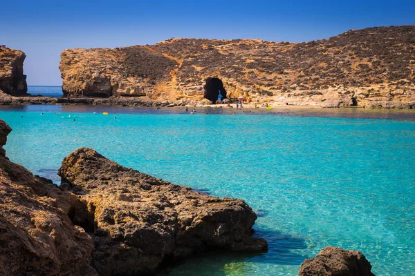 Комино, Мальта - Красивая лазурная морская вода в знаменитой лагуне Комино с подводным плаванием туристов, наслаждающихся летним солнцем — стоковое фото