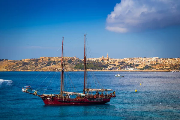 Голубая Лагуна, Мальта - Старая лодка на острове Комино рядом со знаменитой Голубой Лагуной с островом Гоцо и городом Мгарр на заднем плане в солнечный летний день — стоковое фото