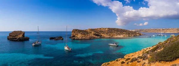 Comino, Malta - Vista panorâmica da famosa e bela Lagoa Azul na ilha de Comino com veleiros, barcos tradicionais Luzzu e turistas desfrutando da água do mar mediterrâneo azul e sol — Fotografia de Stock