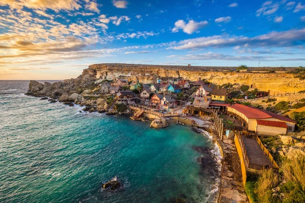 Il-Mellieha, Malta - Sunset at the famous Popeye Village at Anchor Bay. This village was the set in Robert Altman's famous movie 'Popeye' with Robin Williams in the main role. — Stock Photo, Image