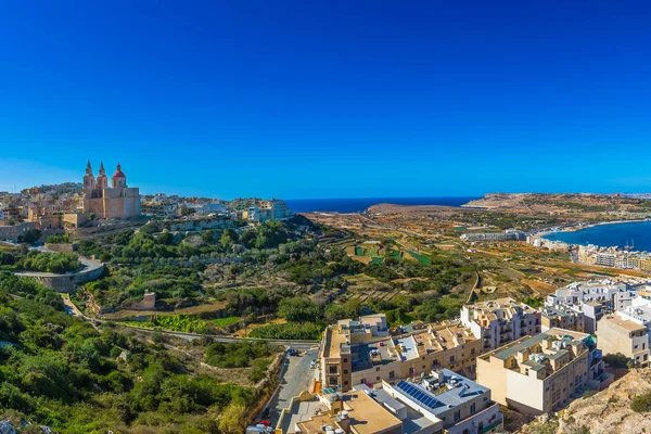 Il-Mellieha, Malta - Hermosa vista panorámica del horizonte de la playa de Mellieha y la ciudad de Mellieha en un brillante día de verano con la Iglesia de París, la Torre Roja de Agatha y la isla de Gozo en el fondo con cielo azul claro — Foto de Stock