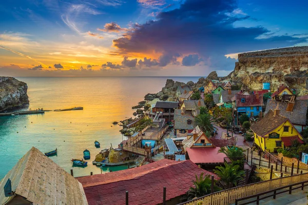 Il-Mellieha, Malta - Skyline view of the famous Popeye Village at Anchor Bay at sunset with amazing colorful clouds and sky — Stock Photo, Image