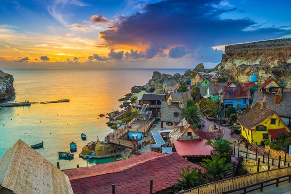 Il-Mellieha, Malta-weergave van de Skyline van de beroemde Popeye Village in Anchor Bay bij zonsondergang met verbazingwekkende kleurrijke wolken en lucht — Stockfoto